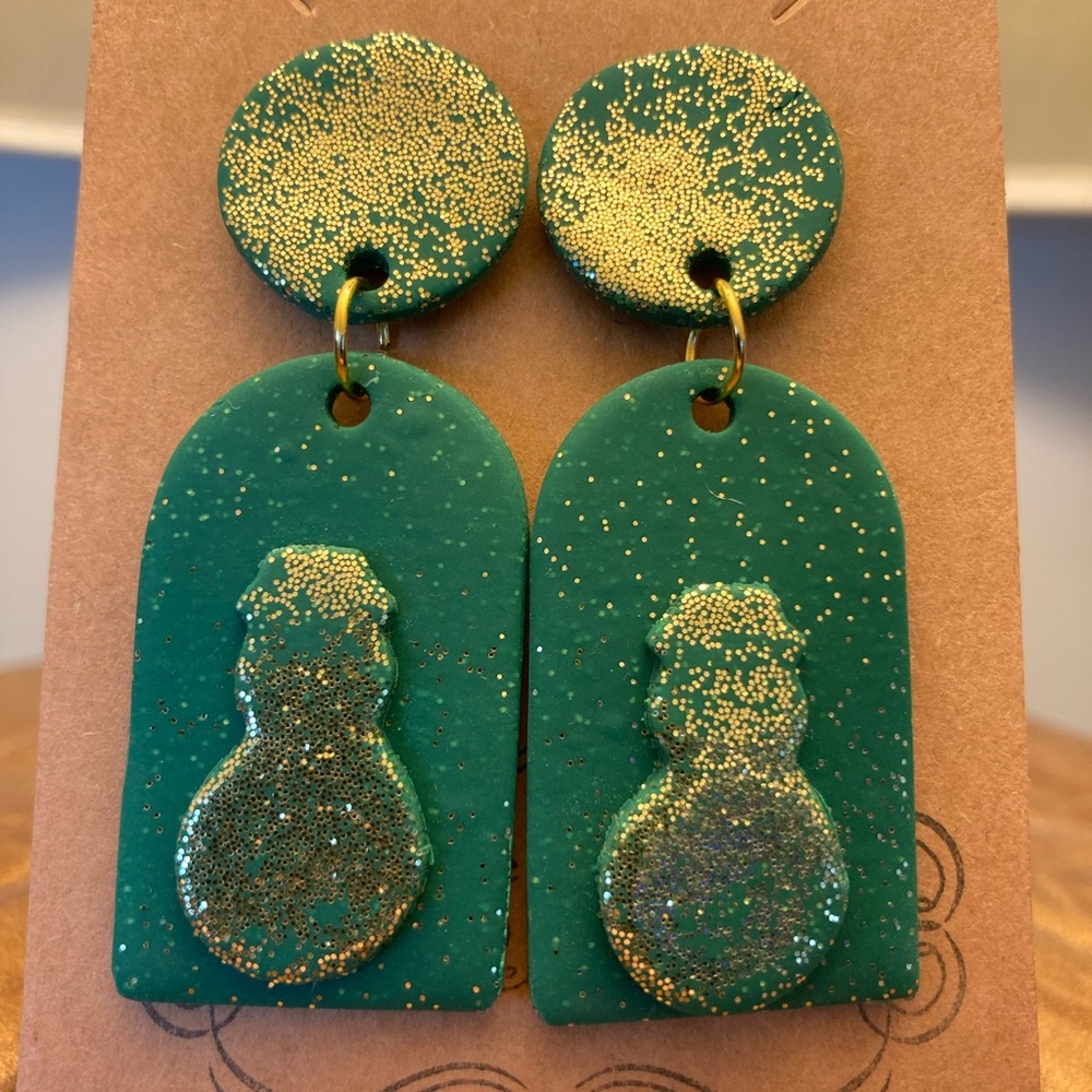 Green dangle earrings with gold glitter and snowman design.
